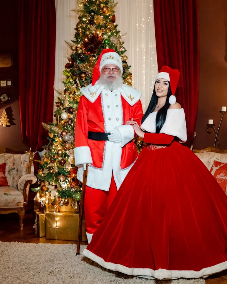 Moș Crăciun și Crăciunița în sufragerie, lângă bradul decorat